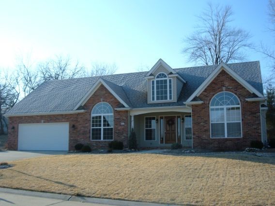 A brick house with a gray roof and arched windows