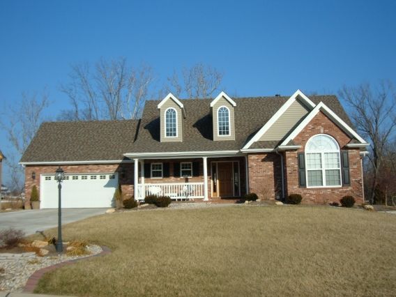A brick house with a brown roof and white trim