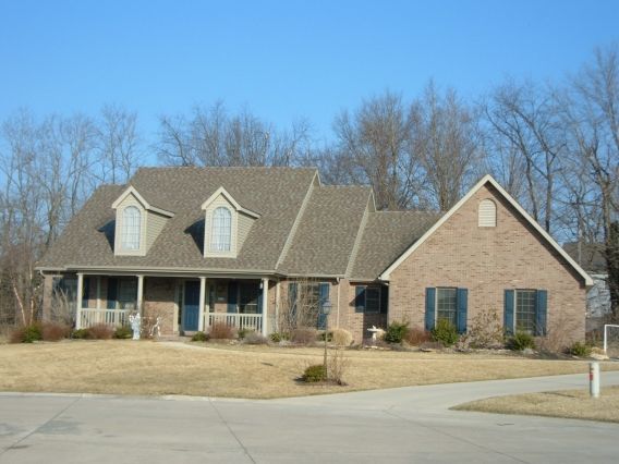 A large brick house with a gray roof and blue shutters