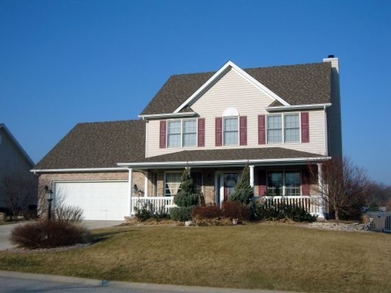 A large house with a white garage door and red shutters
