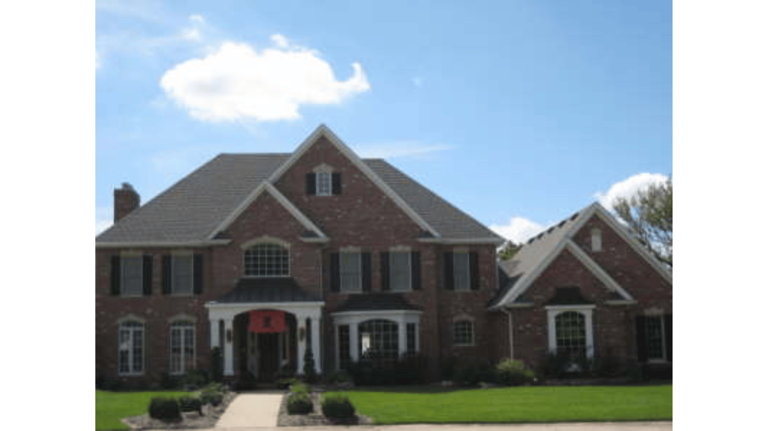 A large brick house with a blue sky in the background