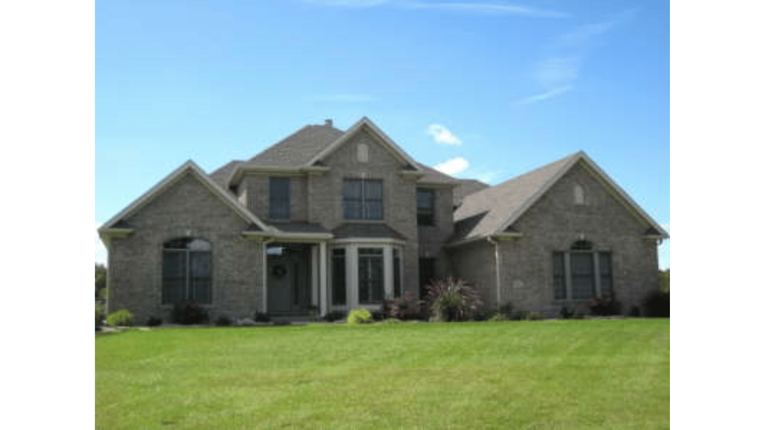 A large brick house with a lush green lawn in front of it