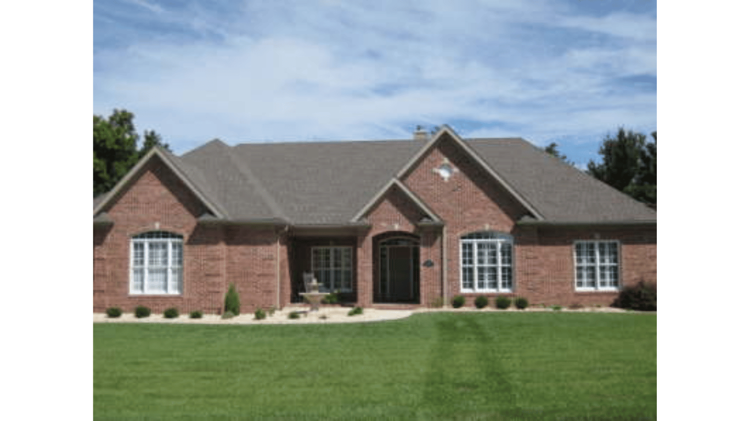 A large brick house with a large lawn in front of it
