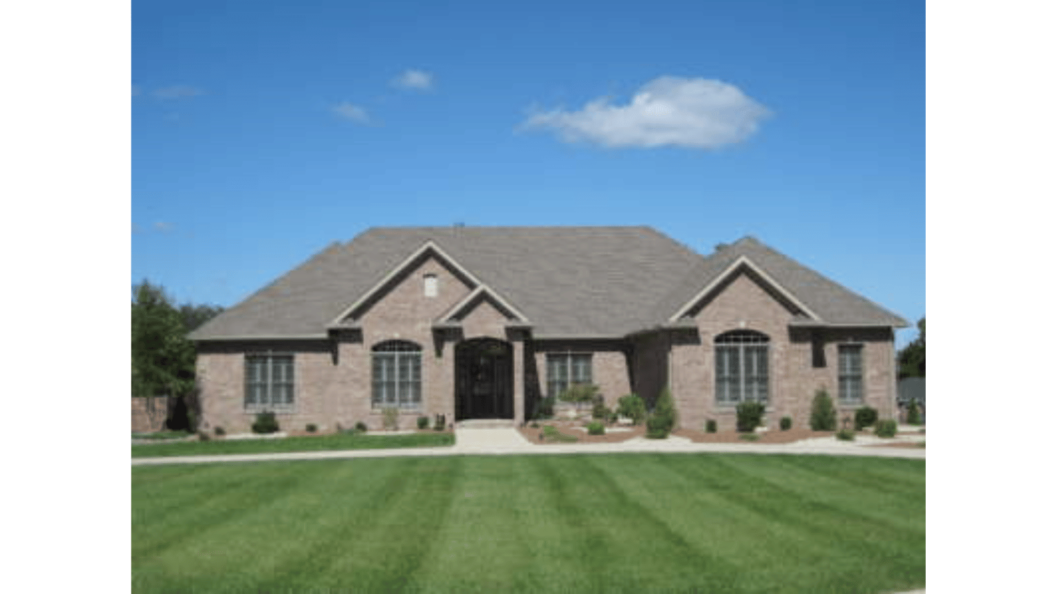 A large brick house with a lush green lawn in front of it