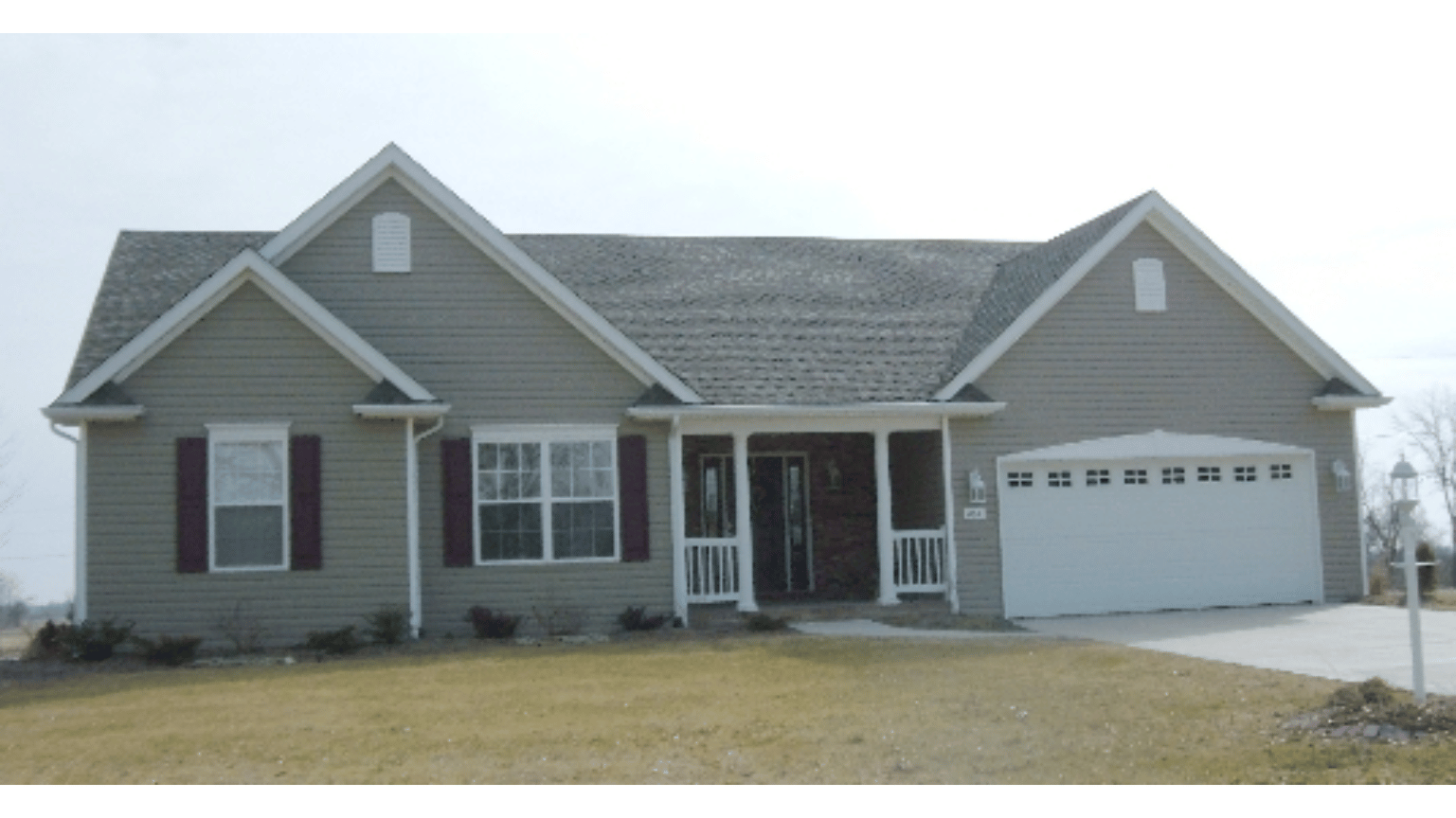 A gray house with a white garage door and black shutters