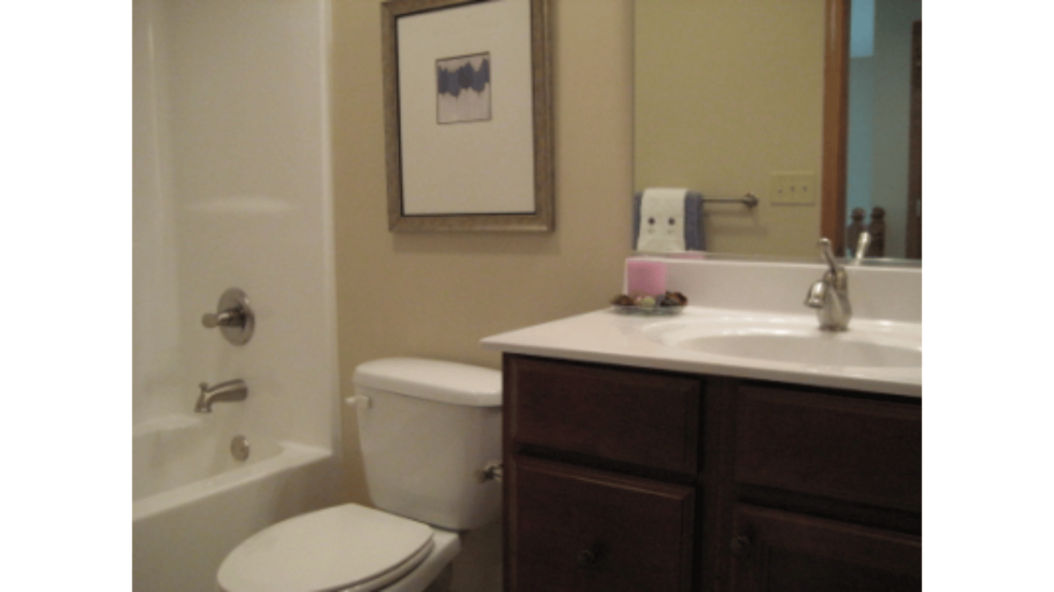 A bathroom with a toilet , sink , tub and mirror.