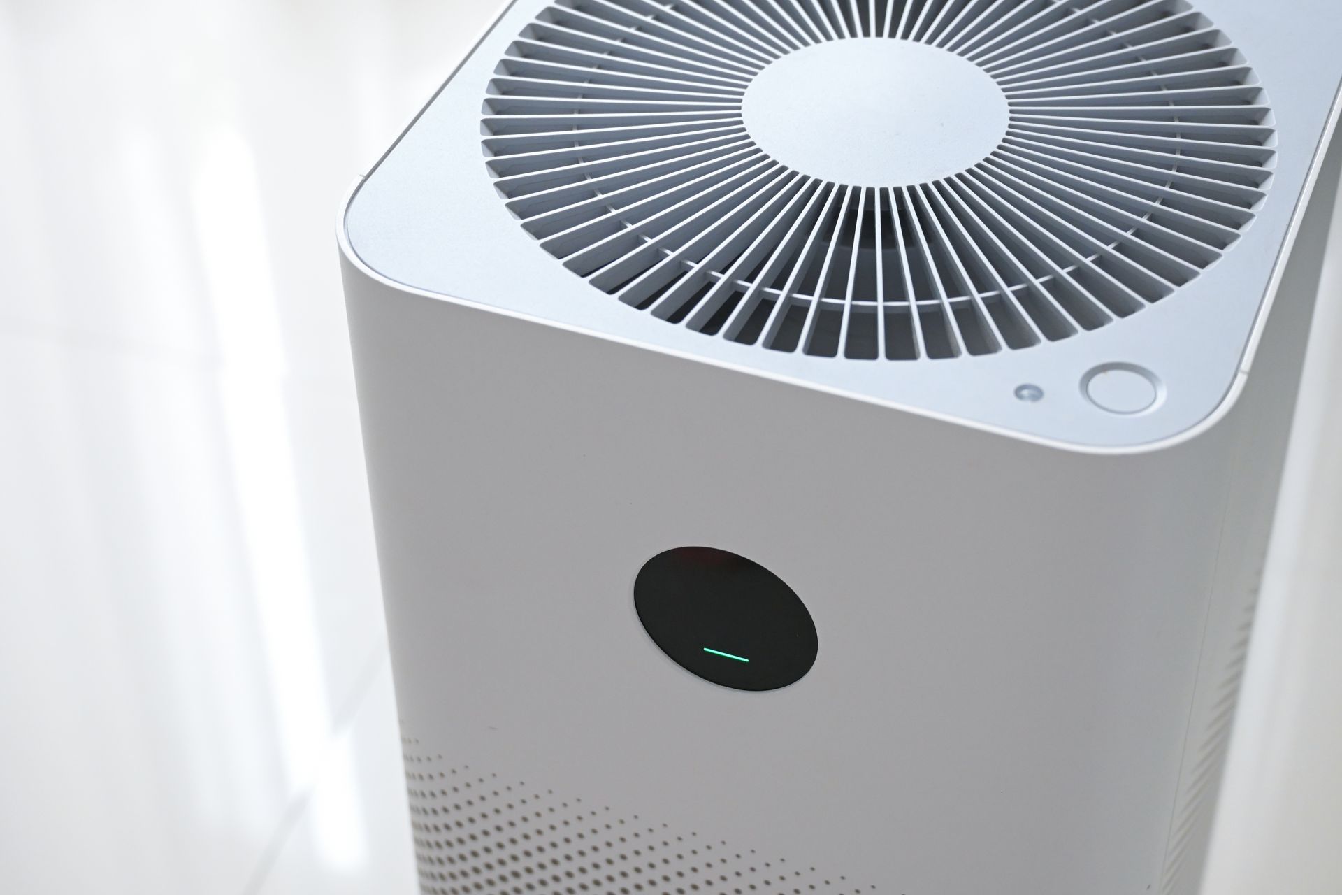 White air purifier with black top vent and circular display near a window