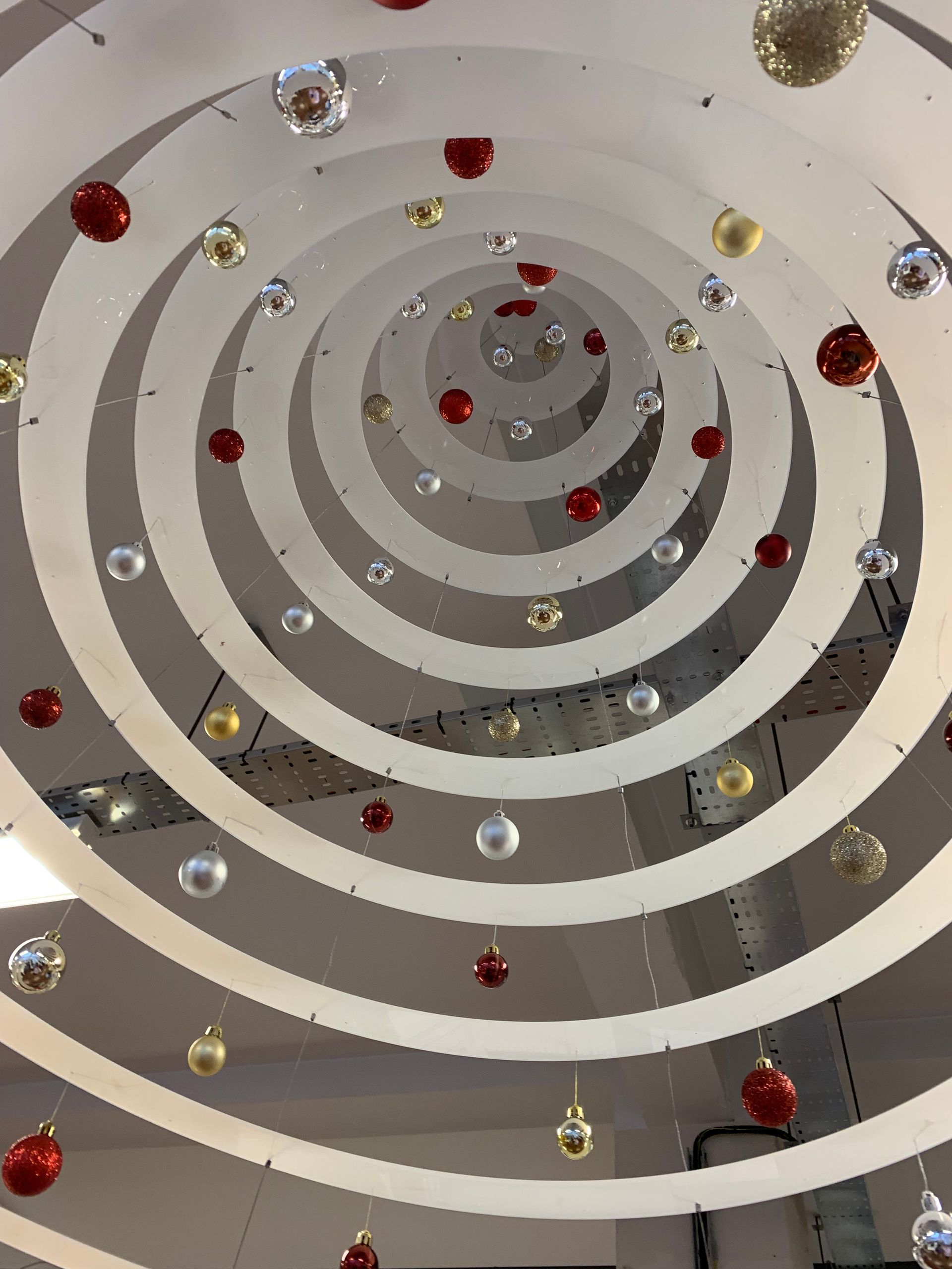 Looking up through Hanging Christmas tree mobile manufactured in white acrylic laser cut to various sized circles decorated with baubles