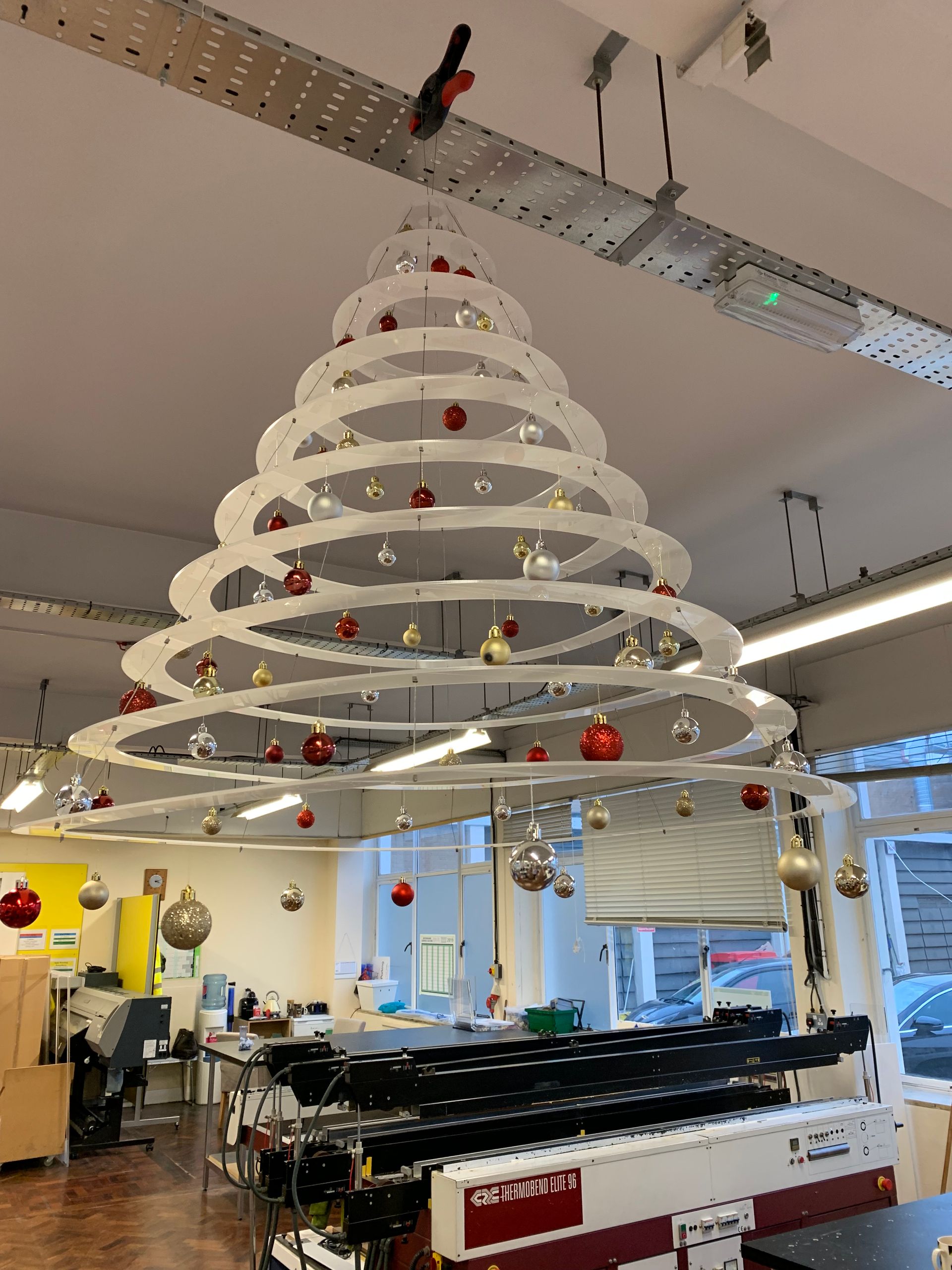 Side view of Hanging Christmas tree mobile manufactured in white acrylic laser cut to various sized circles decorated with baubles