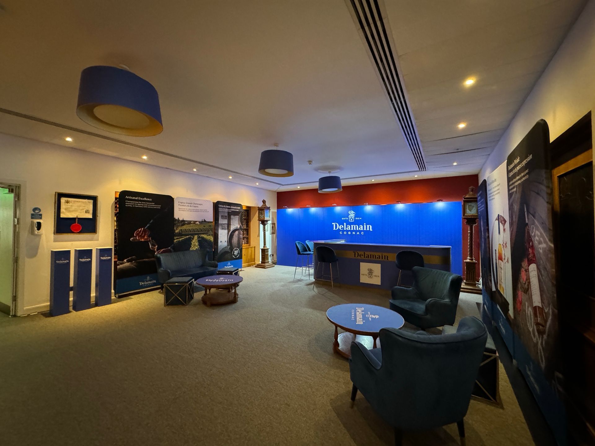 Another view of various branded Delamain Cognac Promotional items including lounge bar, bar tables and printed fabric banners.