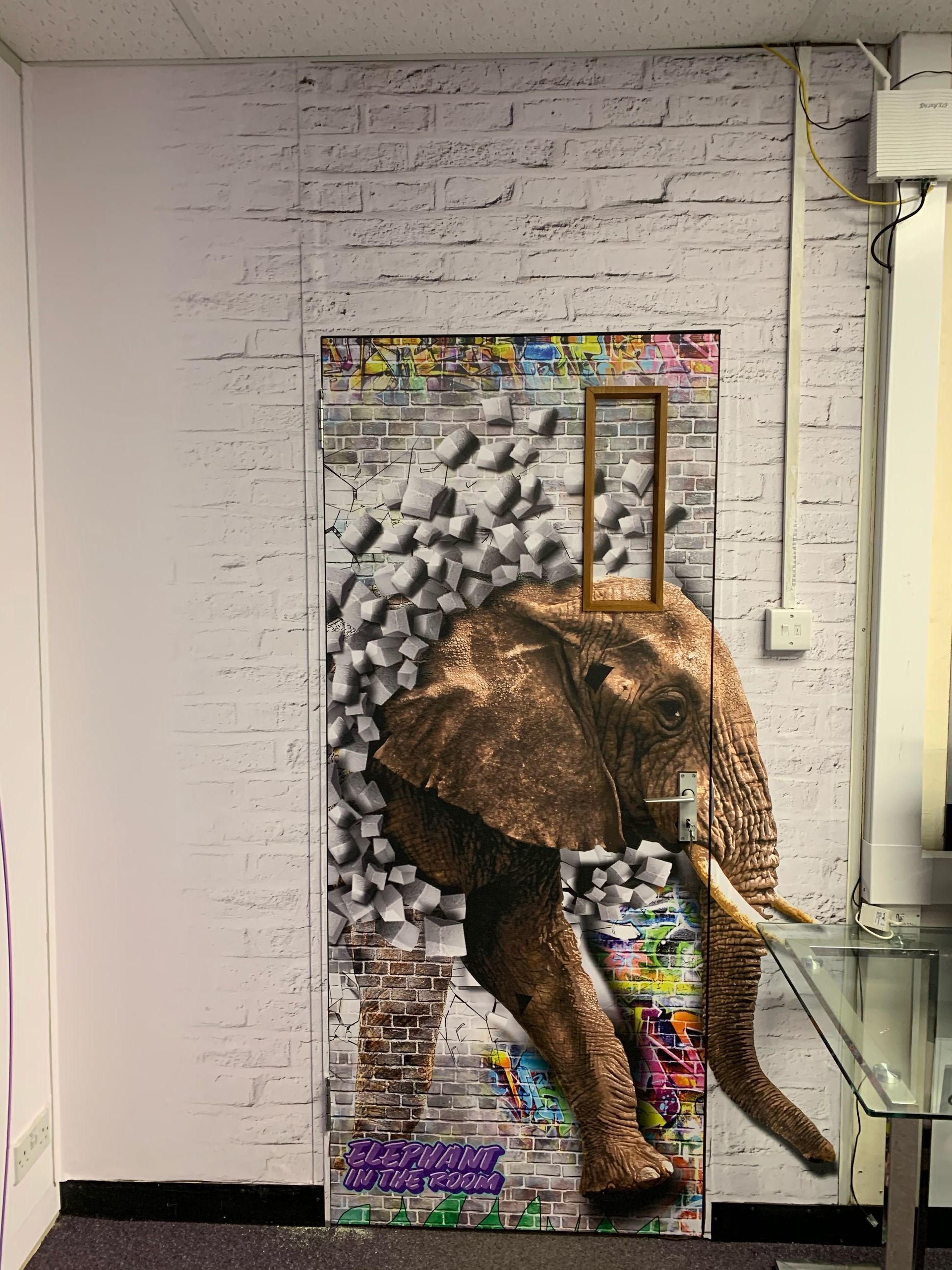 Large format print wall and door cover of elephant breaking through brick wall grafitti