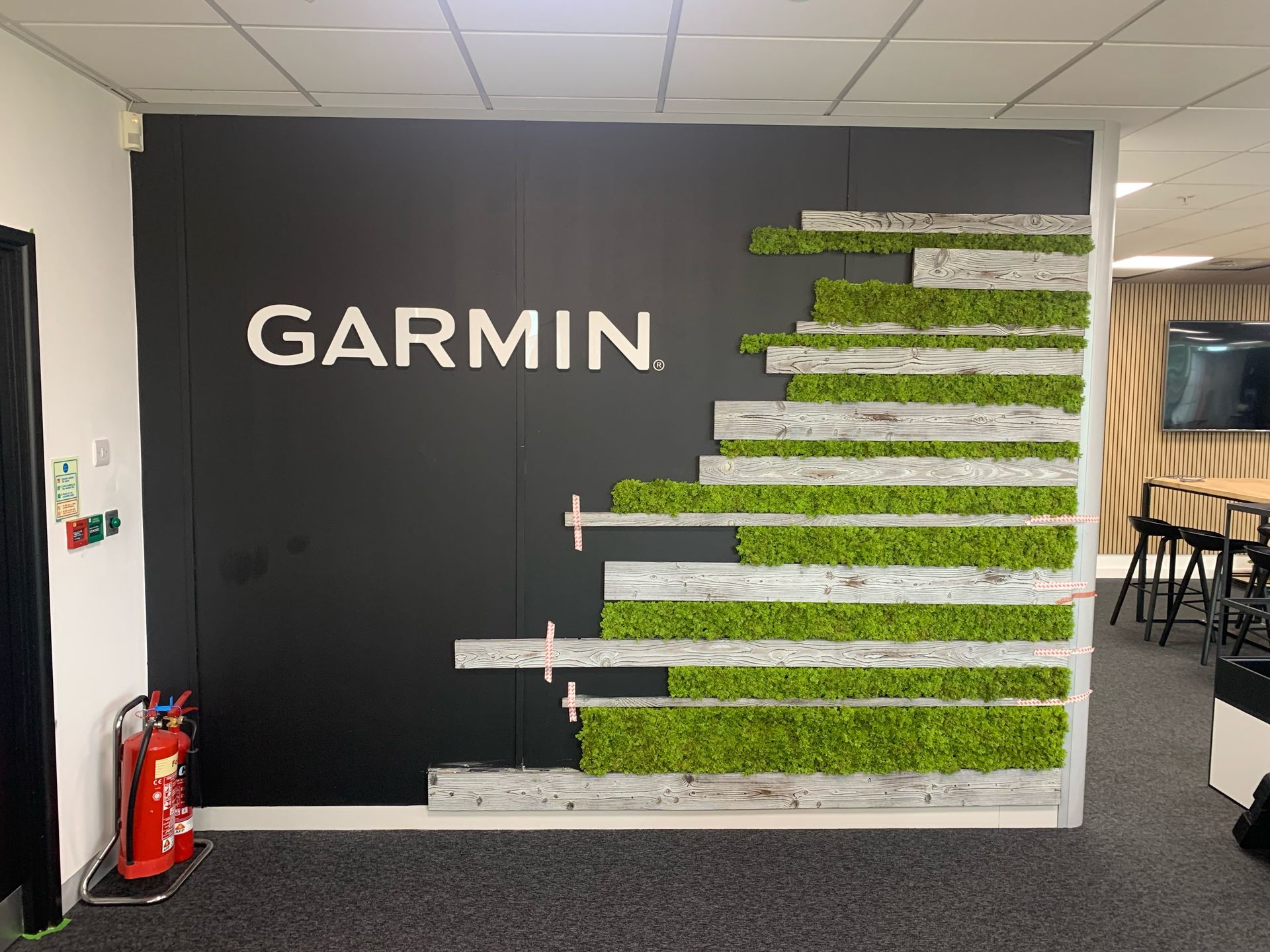 Garmin wall panel with cut wooden slats and fake grass.