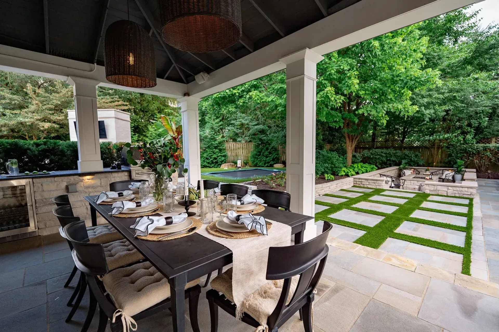 Morganville Landscape Construction, Outdoor dining patio with set table, covered seating, and lush green garden view