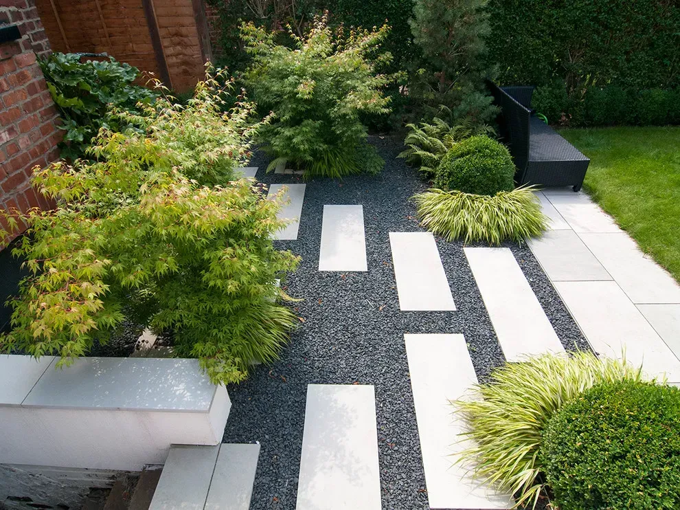 Monmouth County top landscape company. Modern garden path with white stepping stones, shrubs, and a brick wall