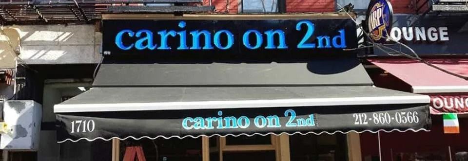 Storefront sign reading “carino on 2nd” in blue lettering above a gray awning.