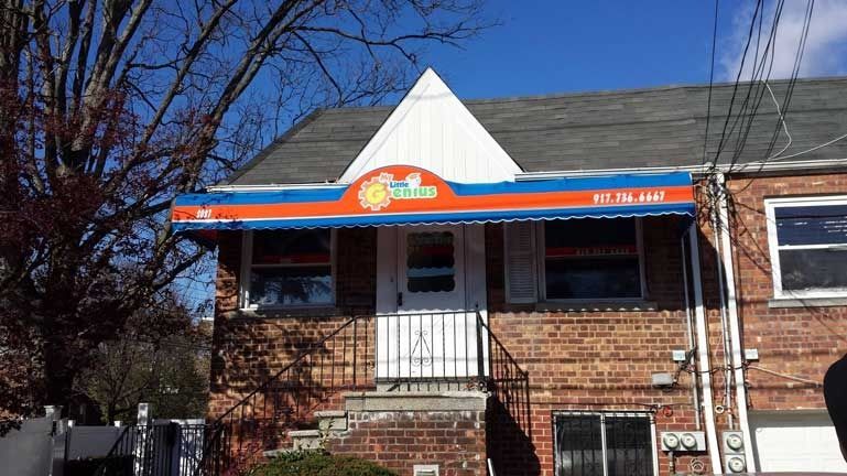 Brick house with a blue-and-orange awning and a small front porch under a clear sky