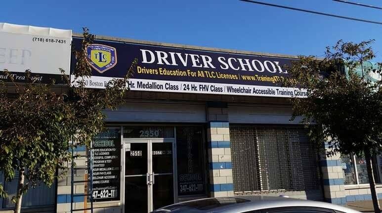 Driver school storefront with blue-and-white sign and shuttered entrance on a street corner