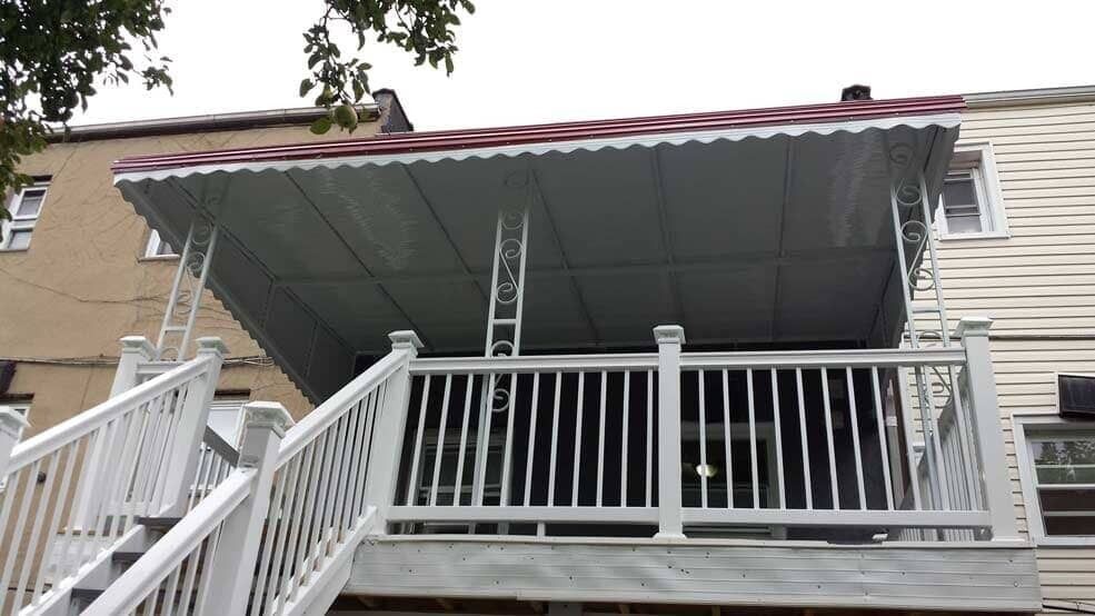 White house porch with red roof, white railings, and a ladder on the front steps