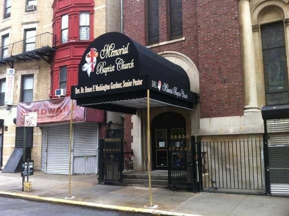 Storefront with a black awning on a brick building and a metal security gate in front.