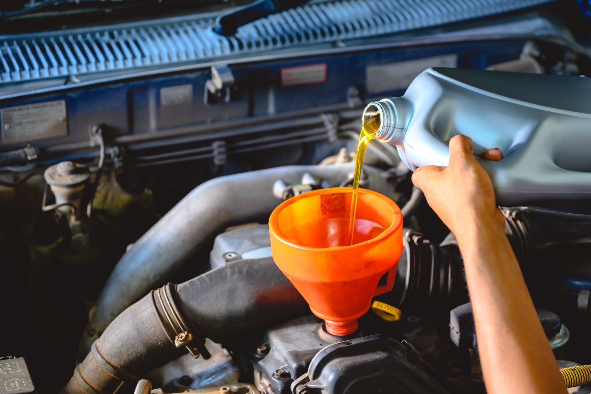 Pouring oil into a car engine through an orange funnel
