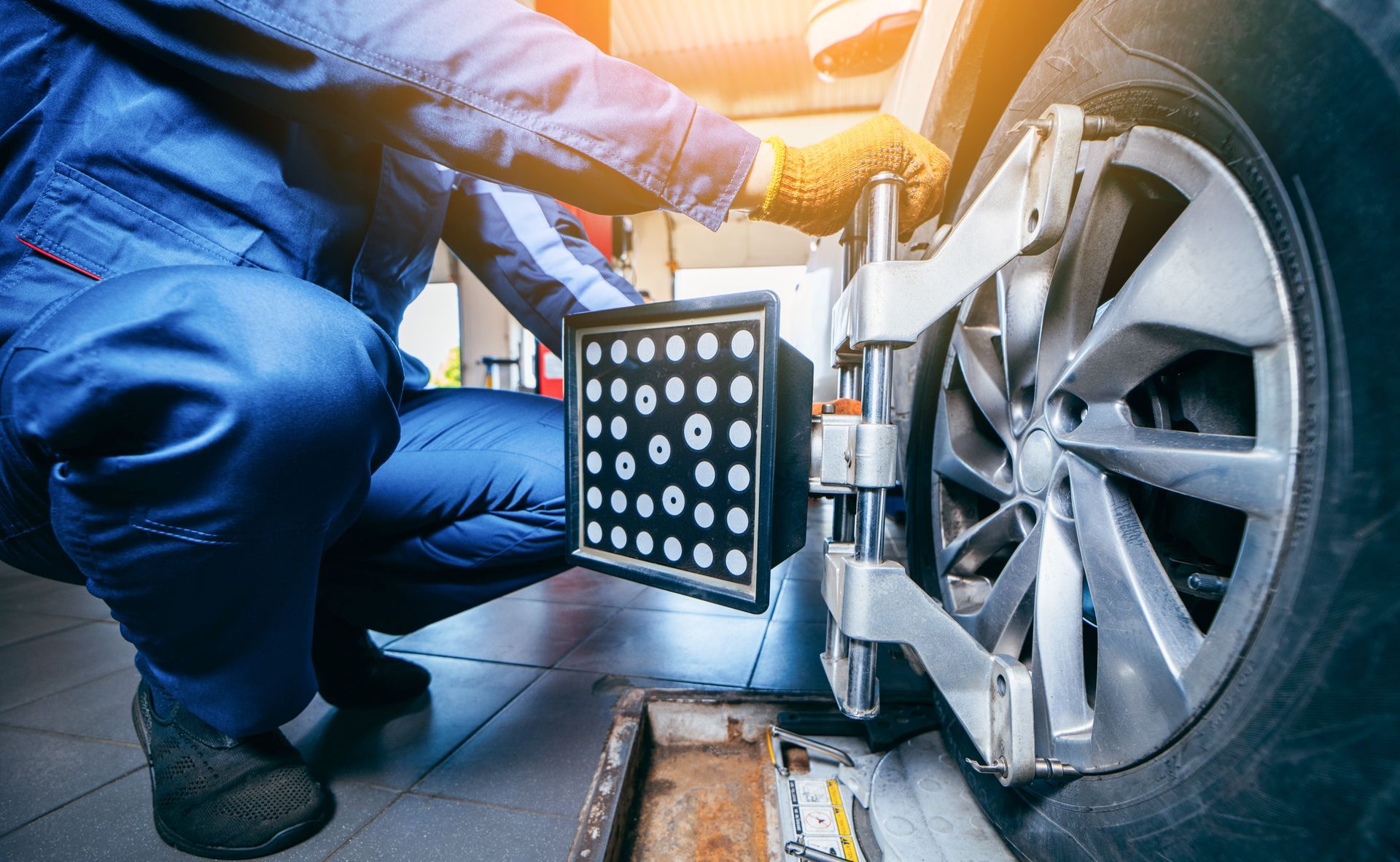 Mechanic inspecting a car wheel with a diagnostic panel in a garage