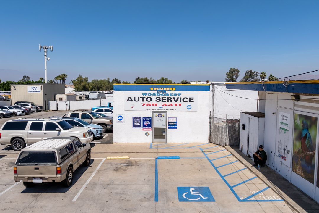 Auto service shop with parking lot, blue handicap spaces, and parked vehicles under a clear sky