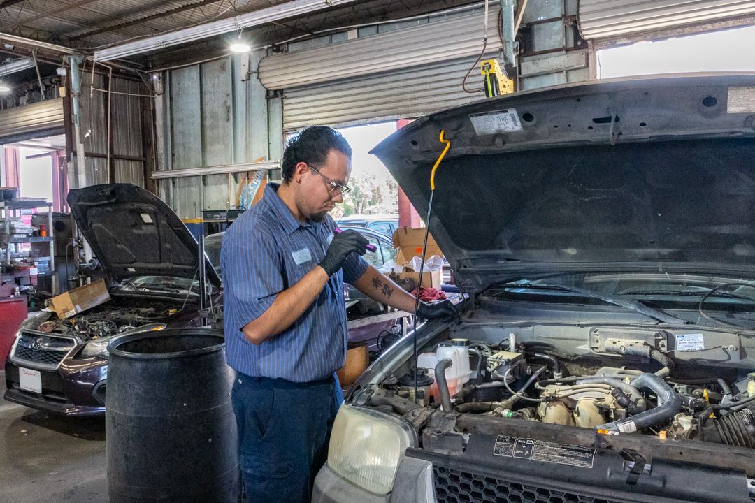 Mechanic inspecting a car engine in an auto repair shop with the hood open