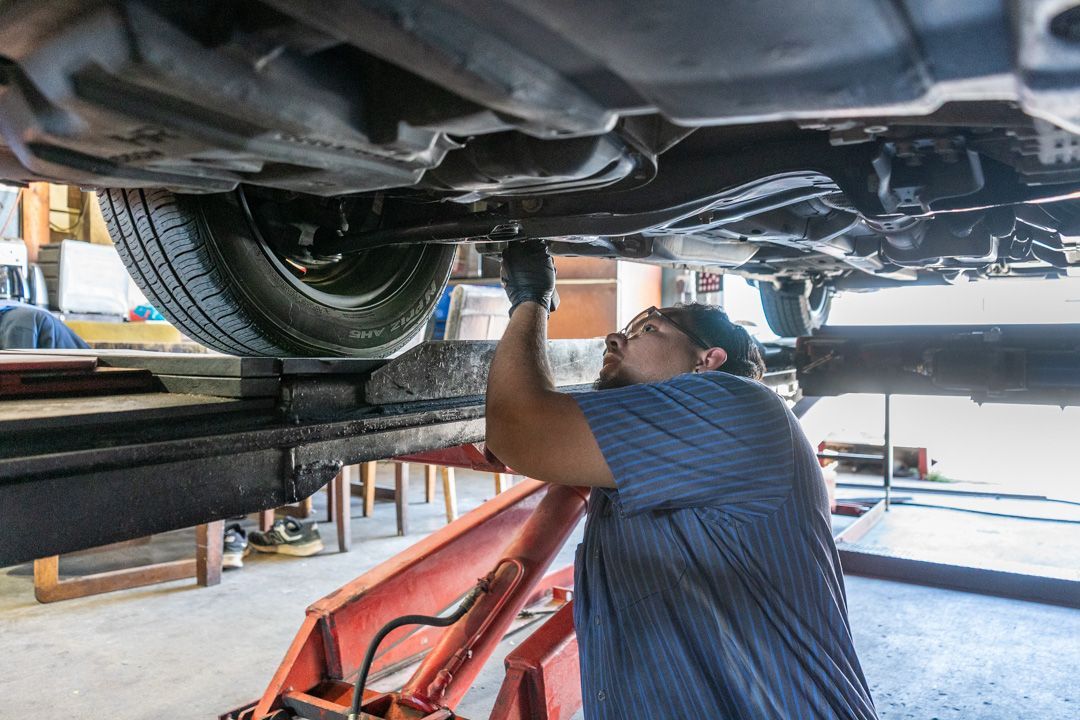 Mechanic inspecting vehicle underside on a lift in an auto repair shop