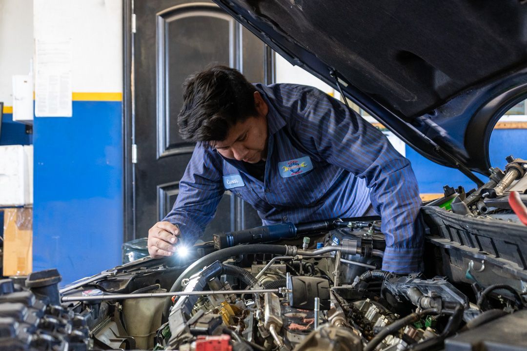 Mechanic inspecting a car engine under the hood in an auto repair shop