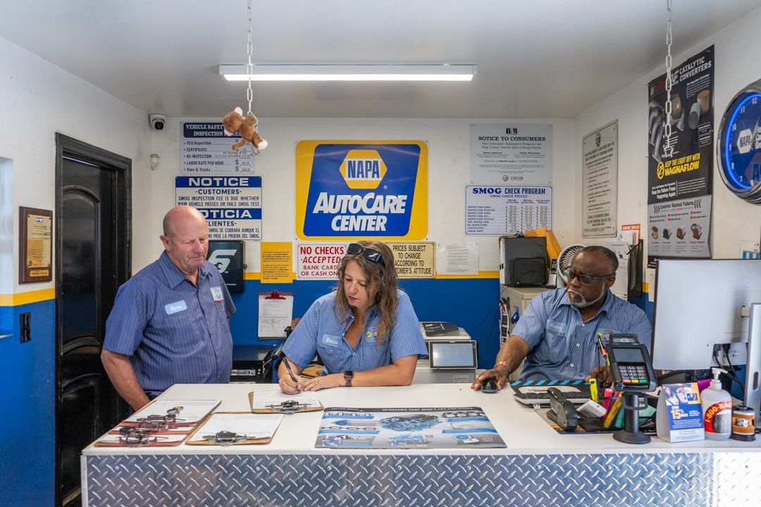 Auto repair shop counter with three staff behind a blue-and-white service desk