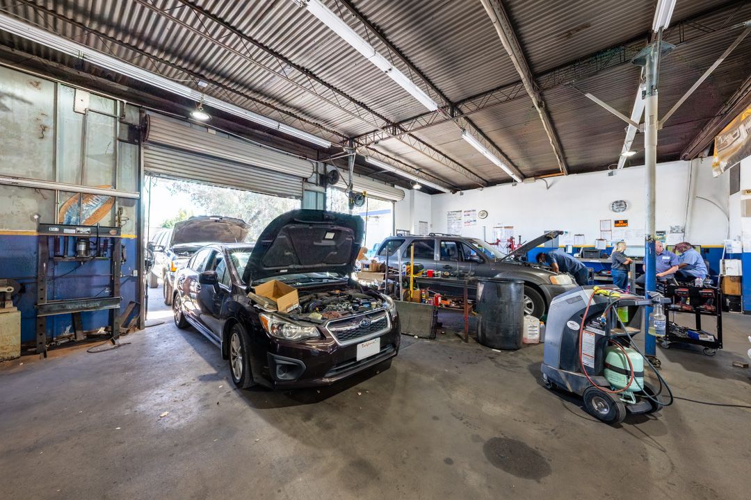 Auto repair shop interior with cars under repair, tools, and equipment on a concrete floor