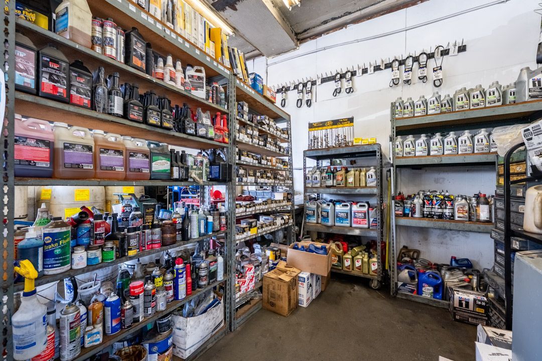 Shelves of assorted hardware and supplies in a small shop aisle, with boxes and bottles stacked throughout