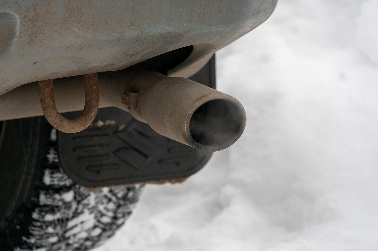 Close-up of a car’s exhaust pipe and rear bumper in snowy conditions
