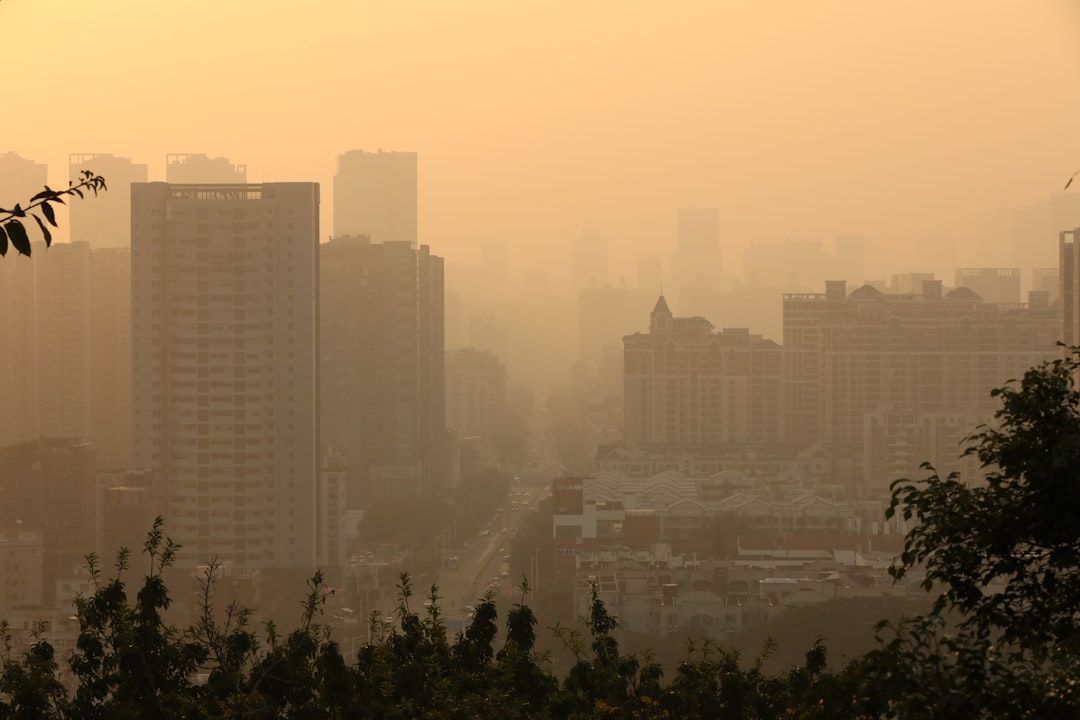Hazy city skyline at sunset with tall buildings silhouetted against an orange sky