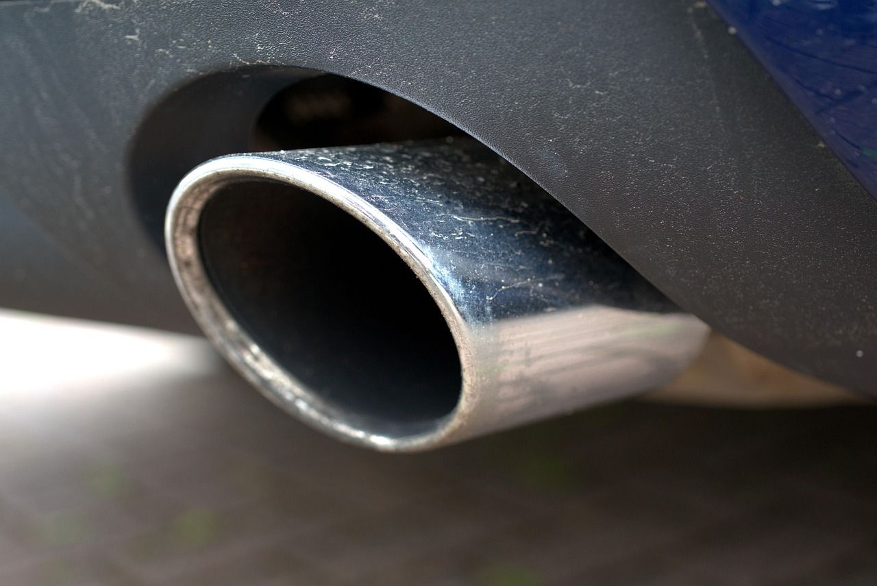 Close-up of a shiny chrome car exhaust pipe under a dark bumper