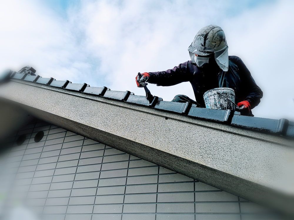 A Man Is Painting The Roof Of A Building — Ballina Painting Service In Alstonville, NSW