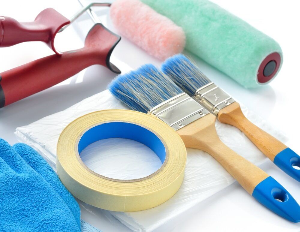 Paint Rollers Paint Brushes Tape And Gloves On A Table — Ballina Painting Service In Lismore, NSW