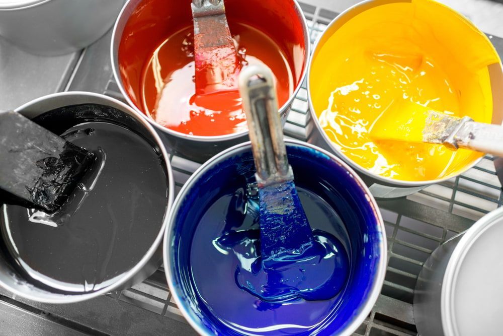 Four Buckets Of Different Colored Paint With Brushes In Them — Ballina Painting Service In Lismore, NSW