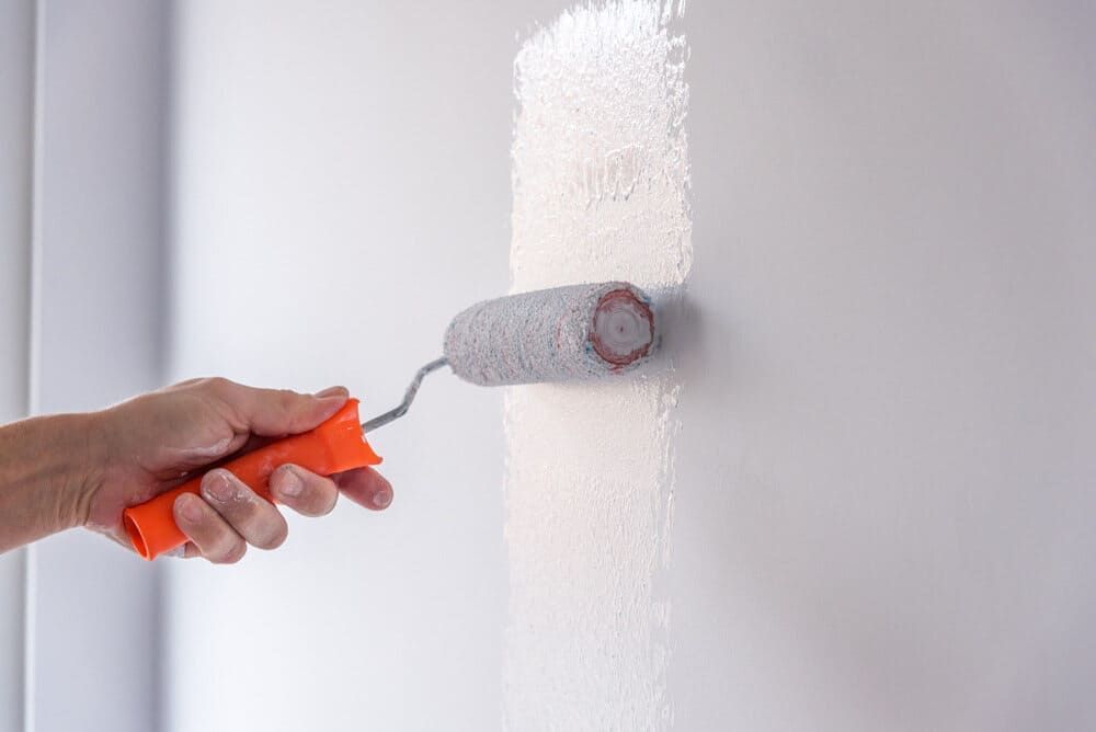 A Person Is Painting A Wall With A Paint Roller — Ballina Painting Service In Alstonville, NSW