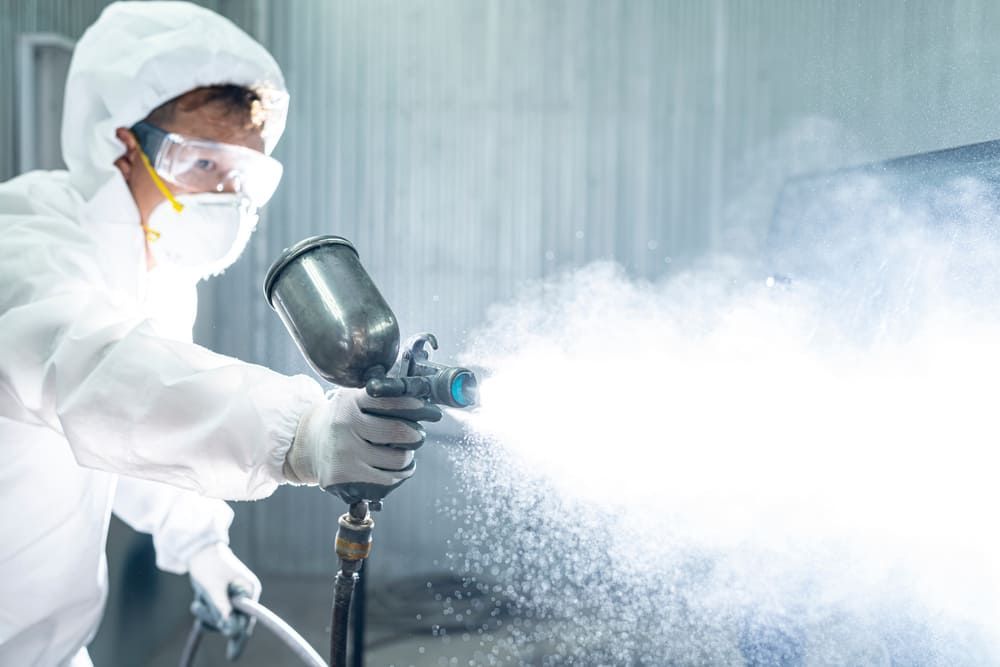 A Man In A Protective Suit Is Spray Painting — Ballina Painting Service In Ballina, NSW