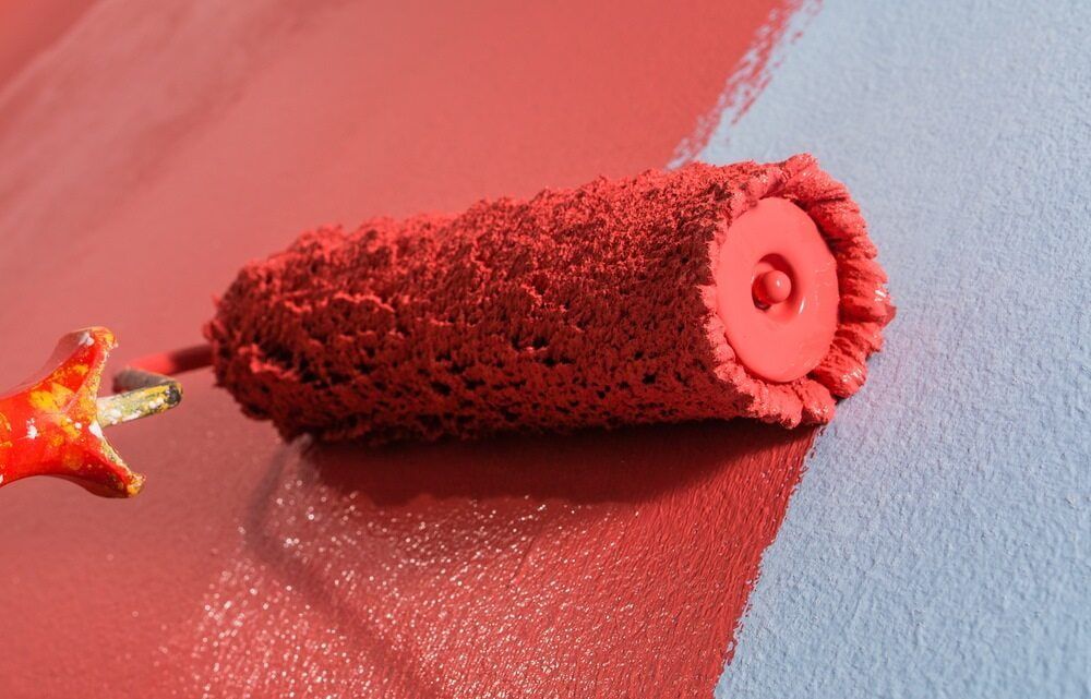A Paint Roller Is Being Used To Paint A Wall Red And Blue — Ballina Painting Service In Evans Head, NSW
