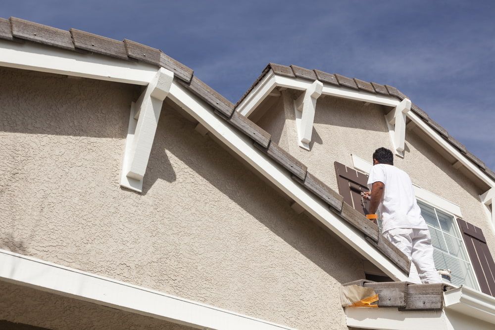 A Man Is Painting The Side Of A House — Ballina Painting Service In Alstonville, NSW