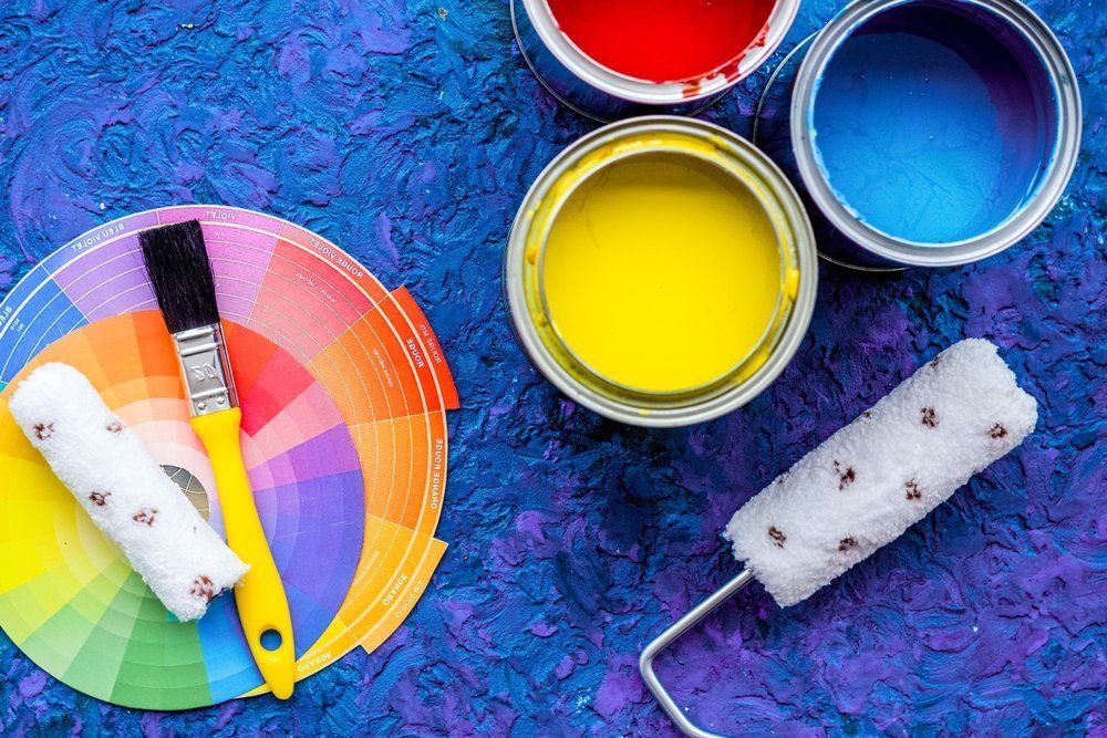 Paint Cans , Brushes , Rollers And A Color Wheel On A Blue Surface — Ballina Painting Service In Ballina, NSW