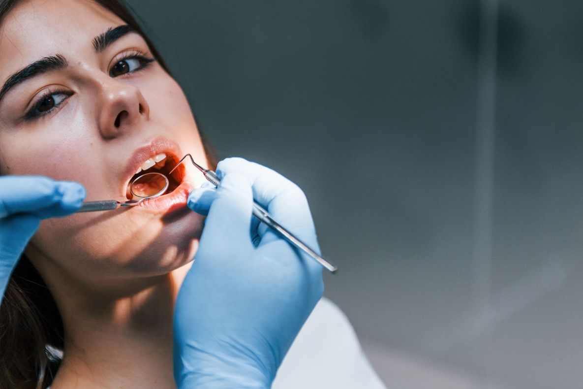 Il dentista esamina la bocca aperta del paziente con le mani guantate e gli strumenti odontoiatrici.