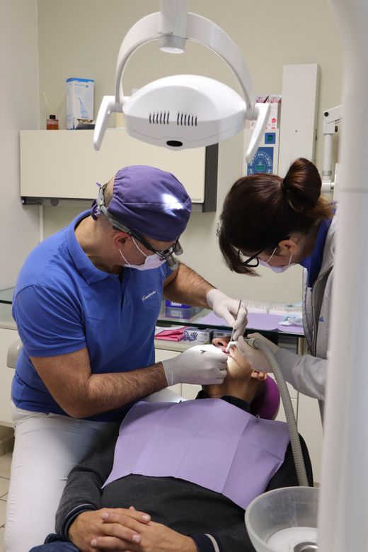 Dentisti che visitano un paziente sulla poltrona odontoiatrica sotto una lampada da visita