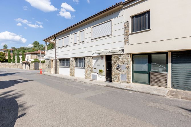 Tranquilla strada residenziale con una fila di case a schiera in pietra bianca e finestre con persiane sotto un cielo azzurro