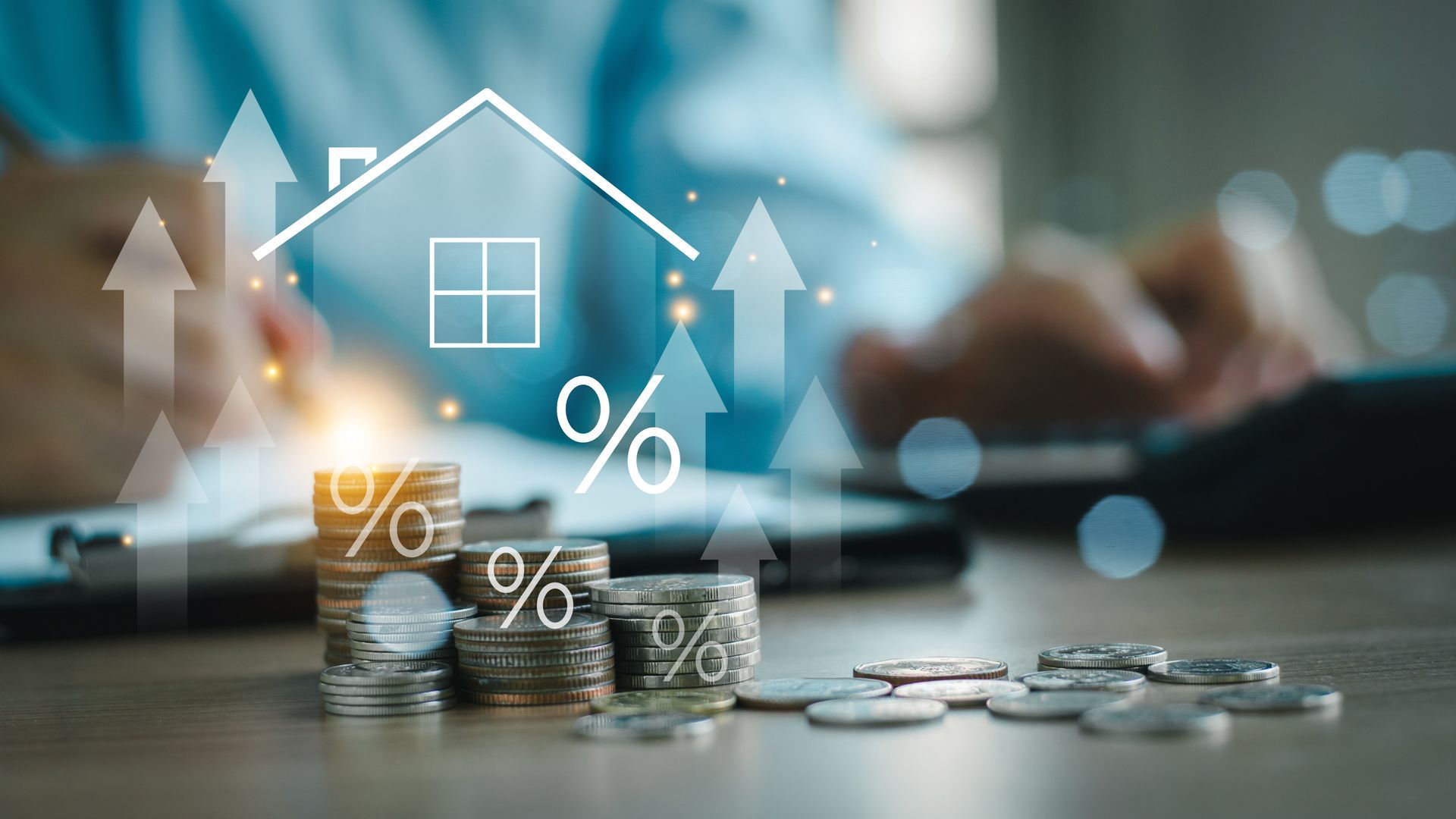 Stack of coins with percentage symbols and upward arrows overlaid with a house icon, person using calculator.