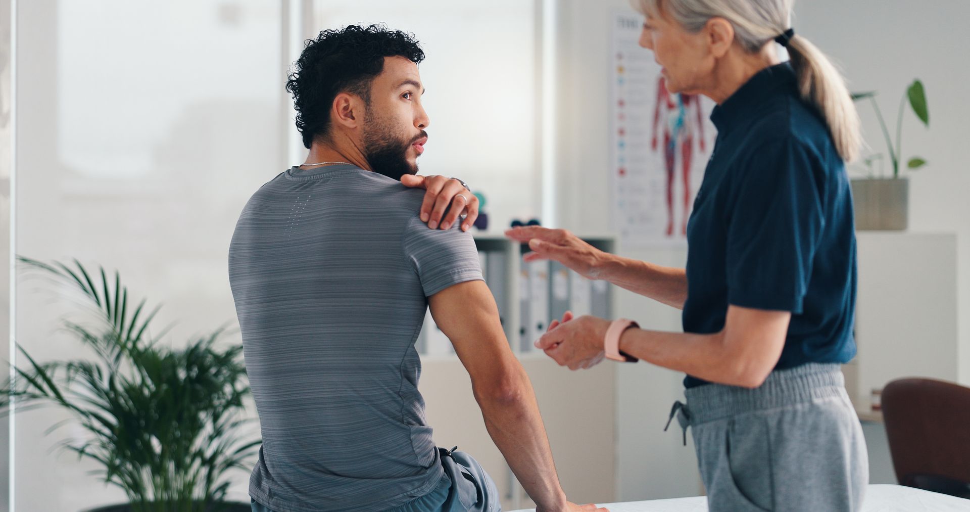 Chiropractor talking of injury, rehabilitation and recovery of joint of male patient muscle.