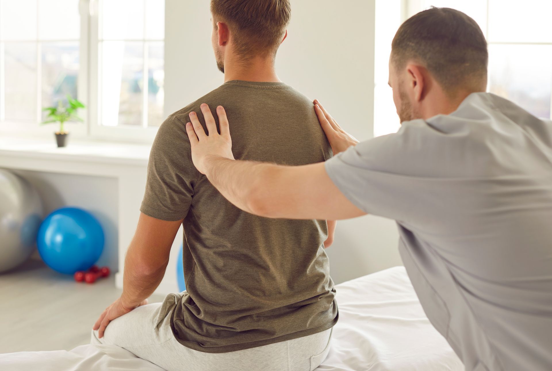 Physical therapist assisting a patient with back exercises on a treatment table