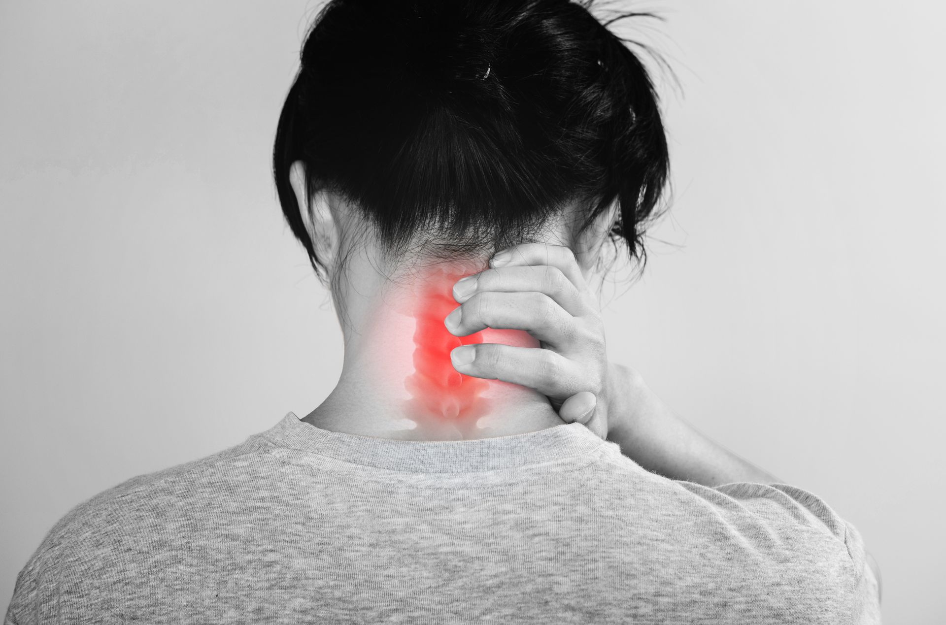 Person holding the back of the neck with highlighted cervical spine discomfort.